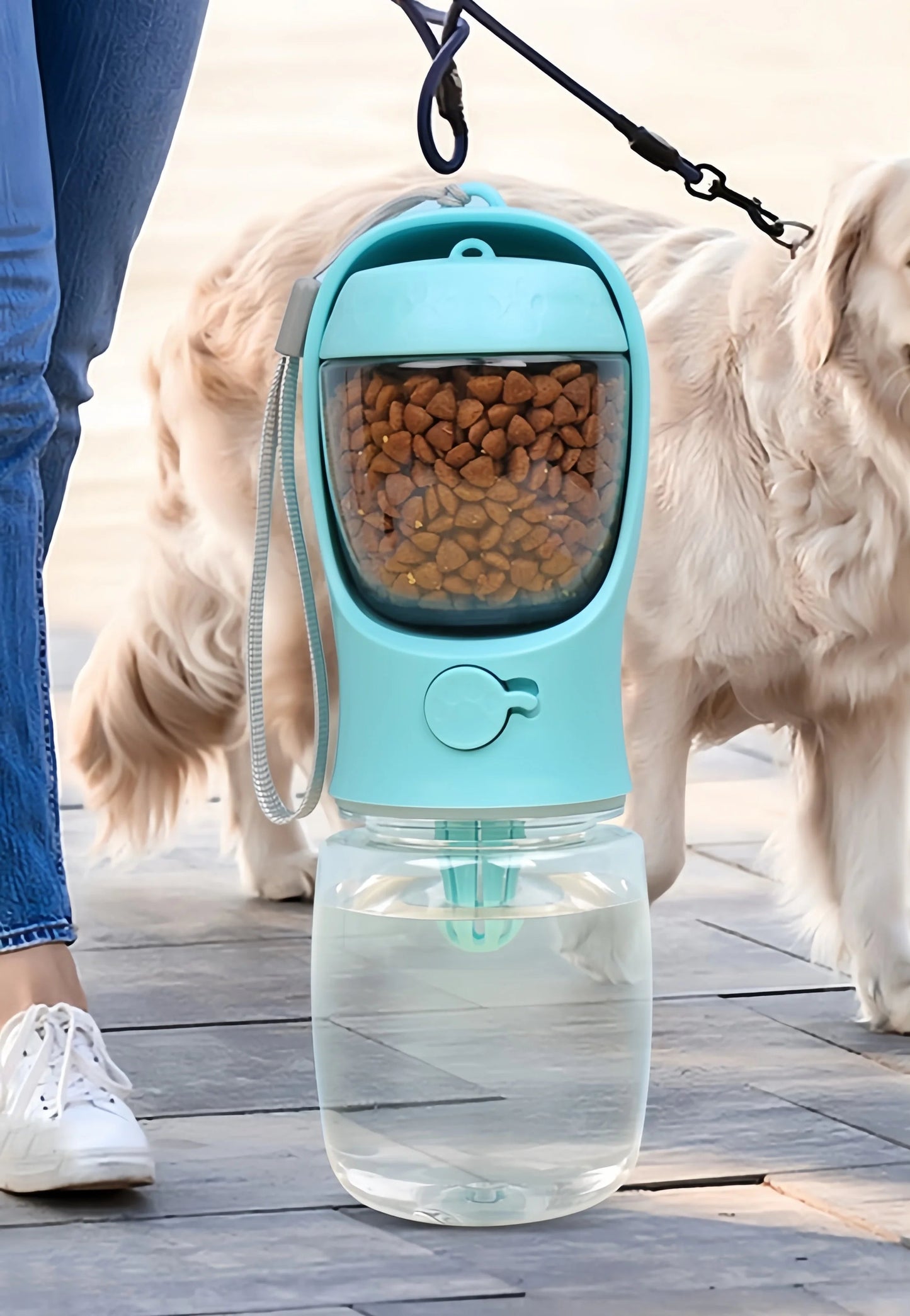 Botella portátil azul para mascotas con compartimentos para agua y comida, ideal para paseos al aire libre, sostenida por una persona junto a un perro golden retriever.